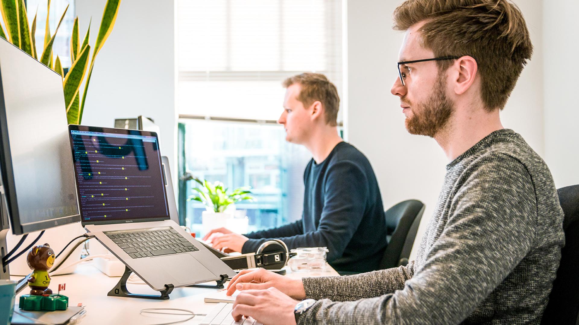 Two men sat at desks working on computers