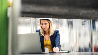 Woman looking at a laptop wearing a hard hat