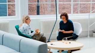 Two women sitting on chairs in an office