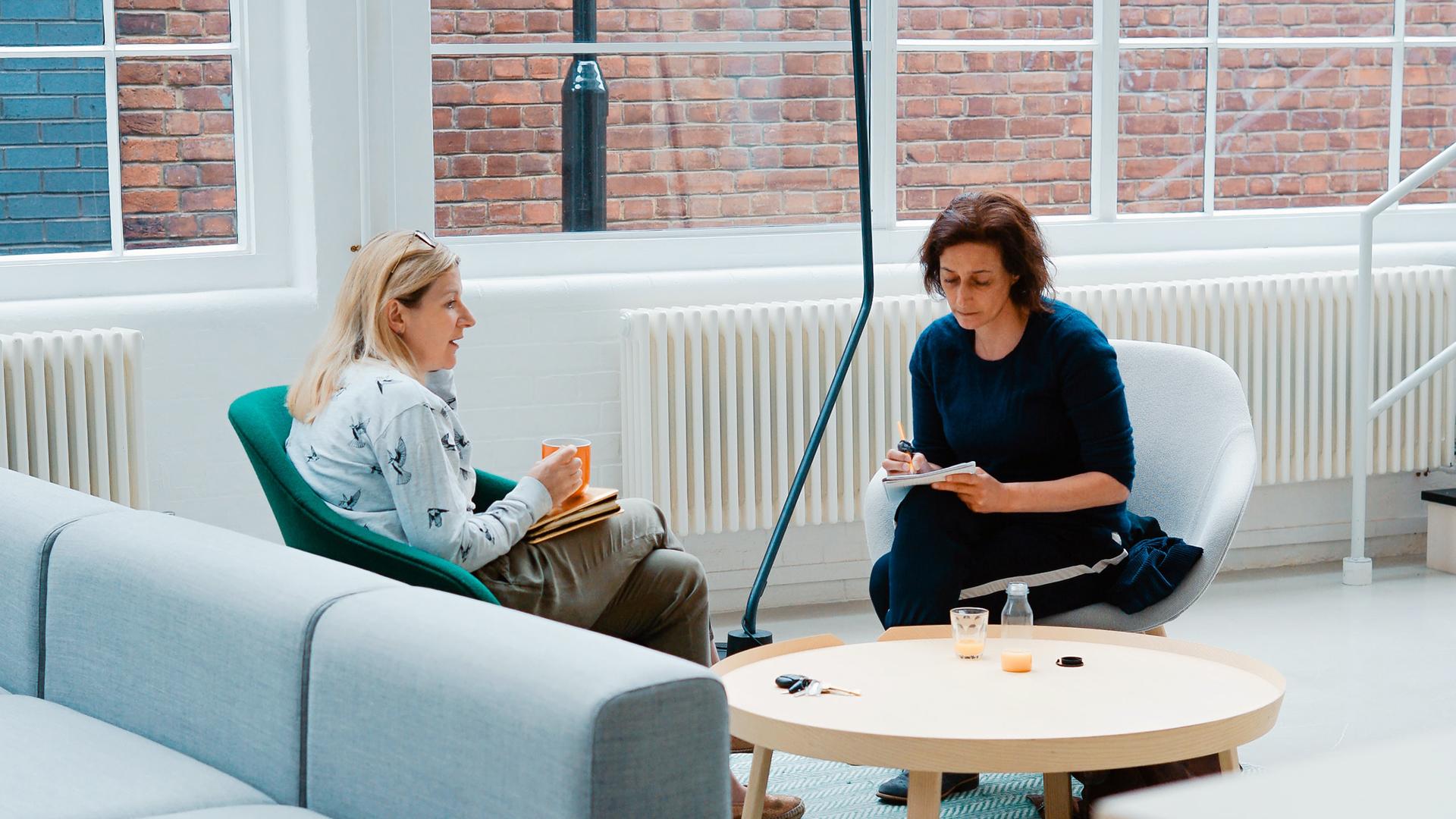 Two women sitting on chairs in an office